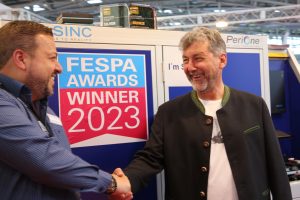 Inhaber Leo Frank von Leo´s Becher und Modico Graphics Sales Director Georg Fradelakis beim Handshake vor der LSINC PeriOne auf der FESPA 2023.